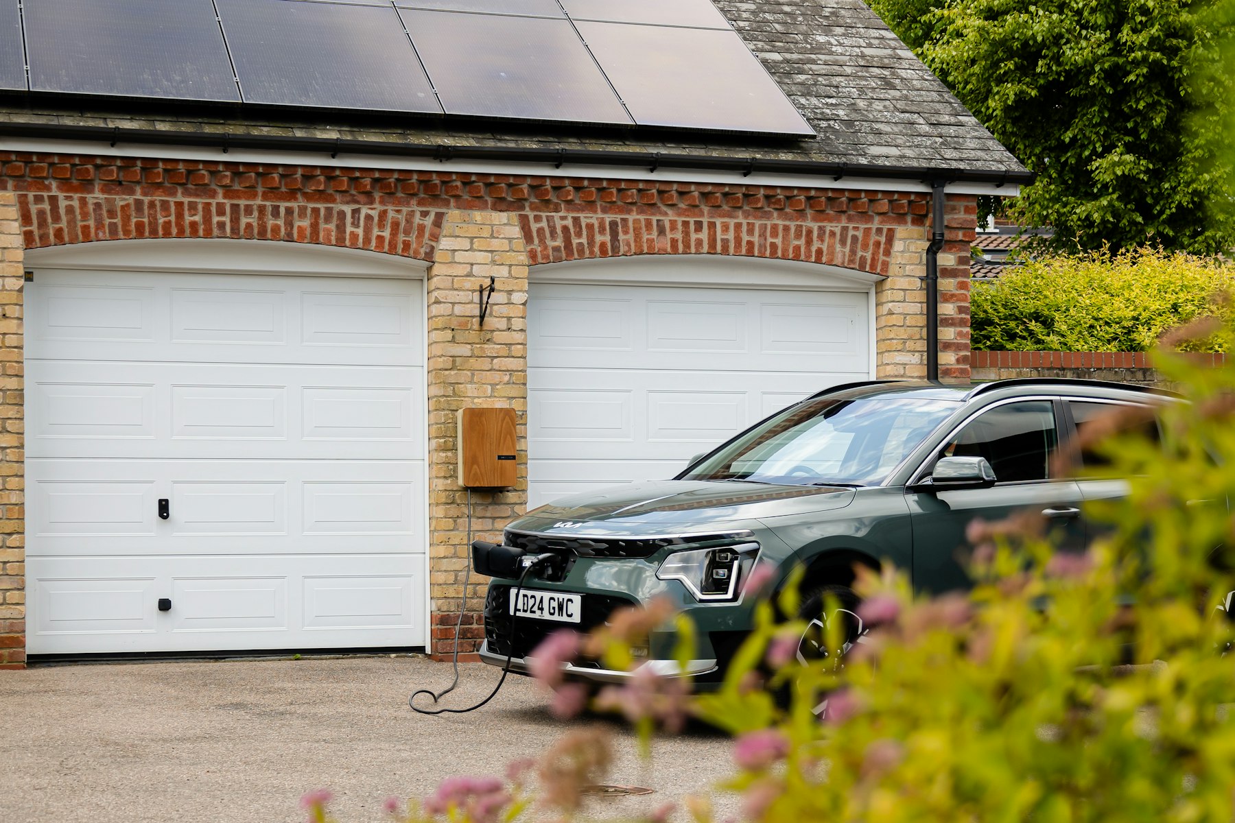 Elbil parkerad framför ett hus med solceller på taket