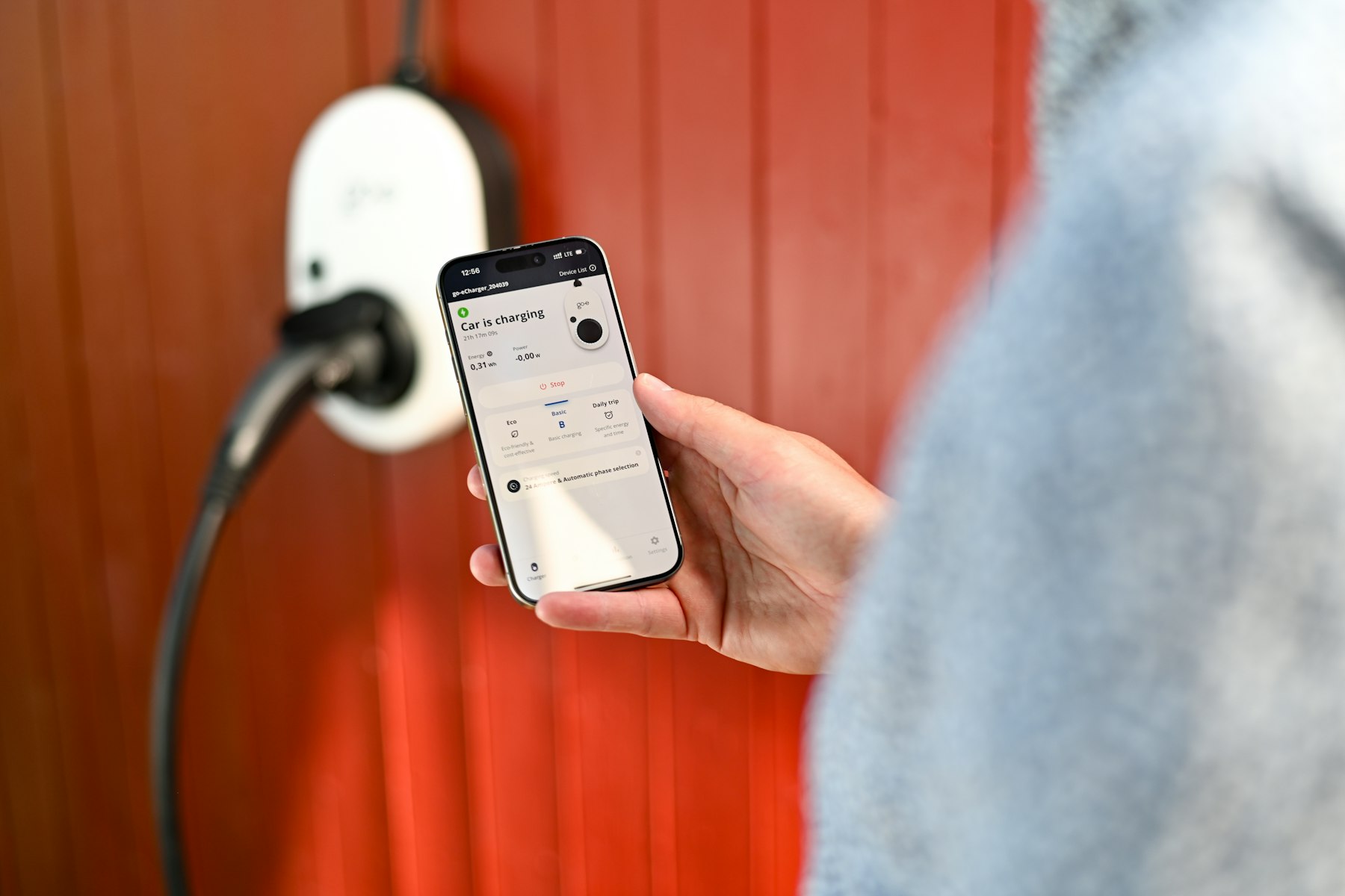 Person styr elbilsladdningen via en app i mobilen